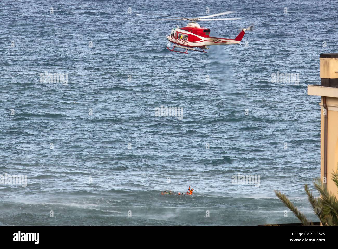 Les nageurs de sauvetage en hélicoptère de Vigili del Fuoco assistent un groupe de nageurs incautieux qui ont été emmenés par la mer agitée et les soulèvent par treuil sur leur hélicoptère. Banque D'Images