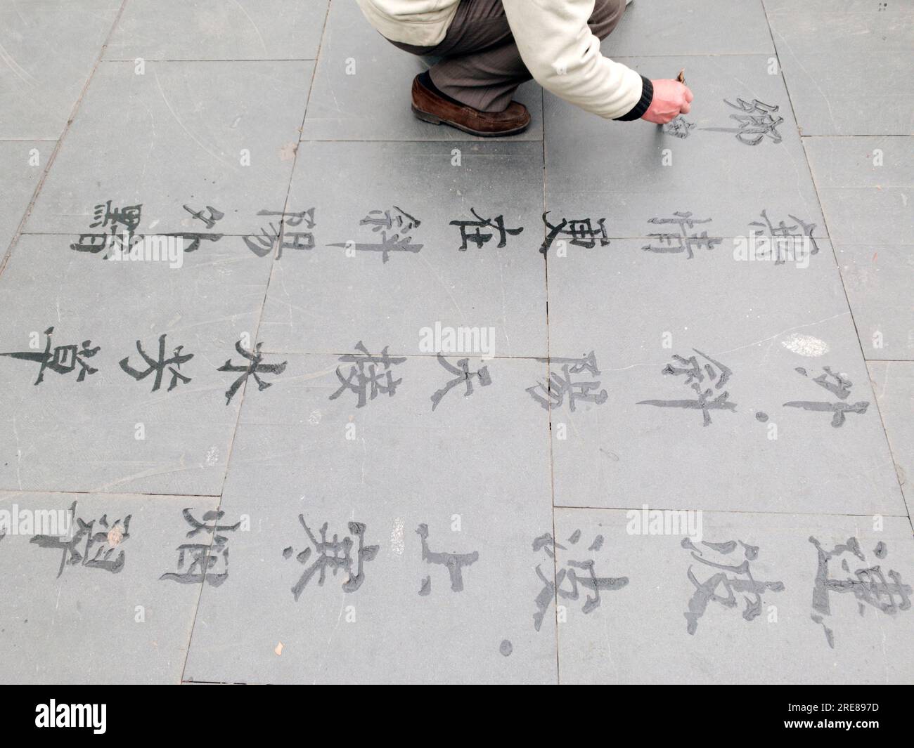 Gros plan d'un homme faisant de la calligraphie d'eau sur le trottoir, Shanghai, Chine Banque D'Images