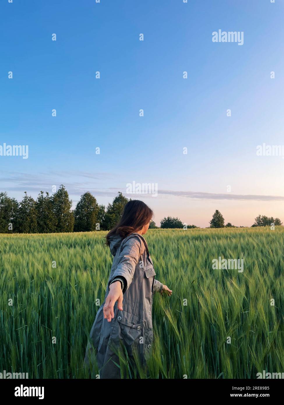 Femme avec le bras tendu marchant dans un champ le matin, Biélorussie Banque D'Images