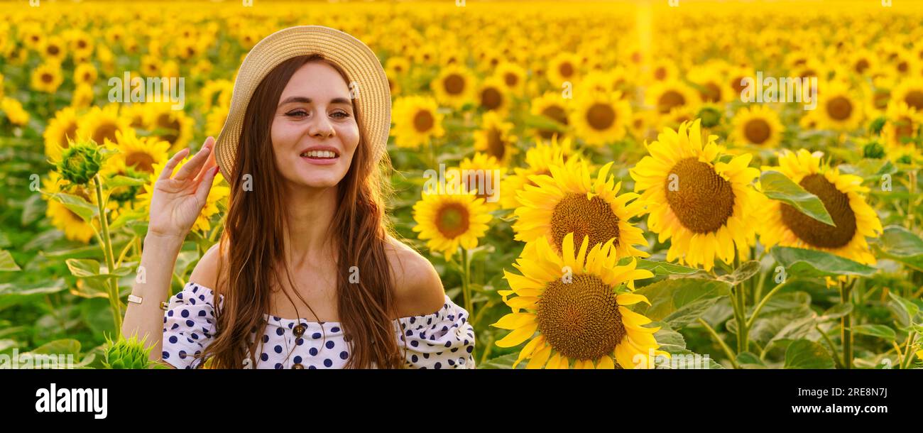 bannière heureuse jeune femme dans un chapeau de paille au coucher du soleil posant dans un champ de tournesols, contre le ciel Banque D'Images