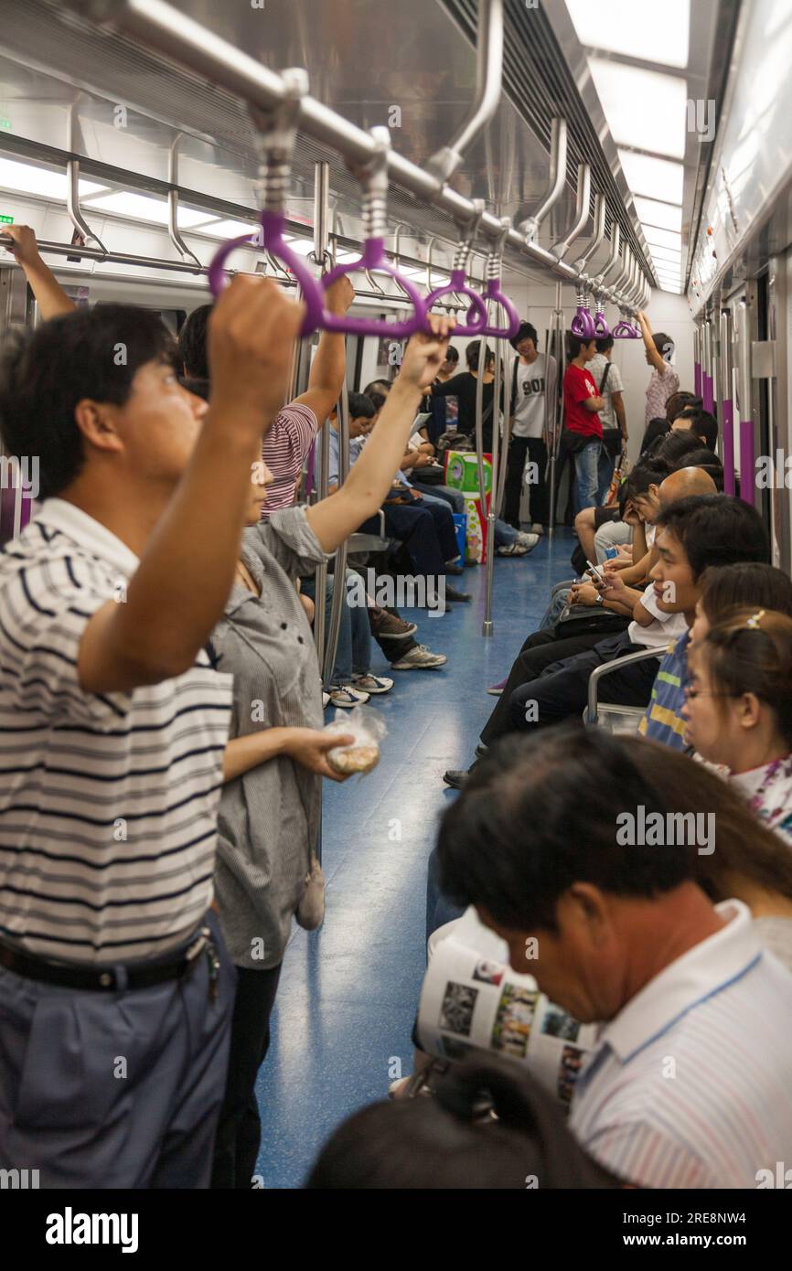 À l'intérieur du compartiment de voiture de train de tube de métro avec des navetteurs chinois / passagers de banlieue. Système souterrain. Pékin, Chine. (125) Banque D'Images