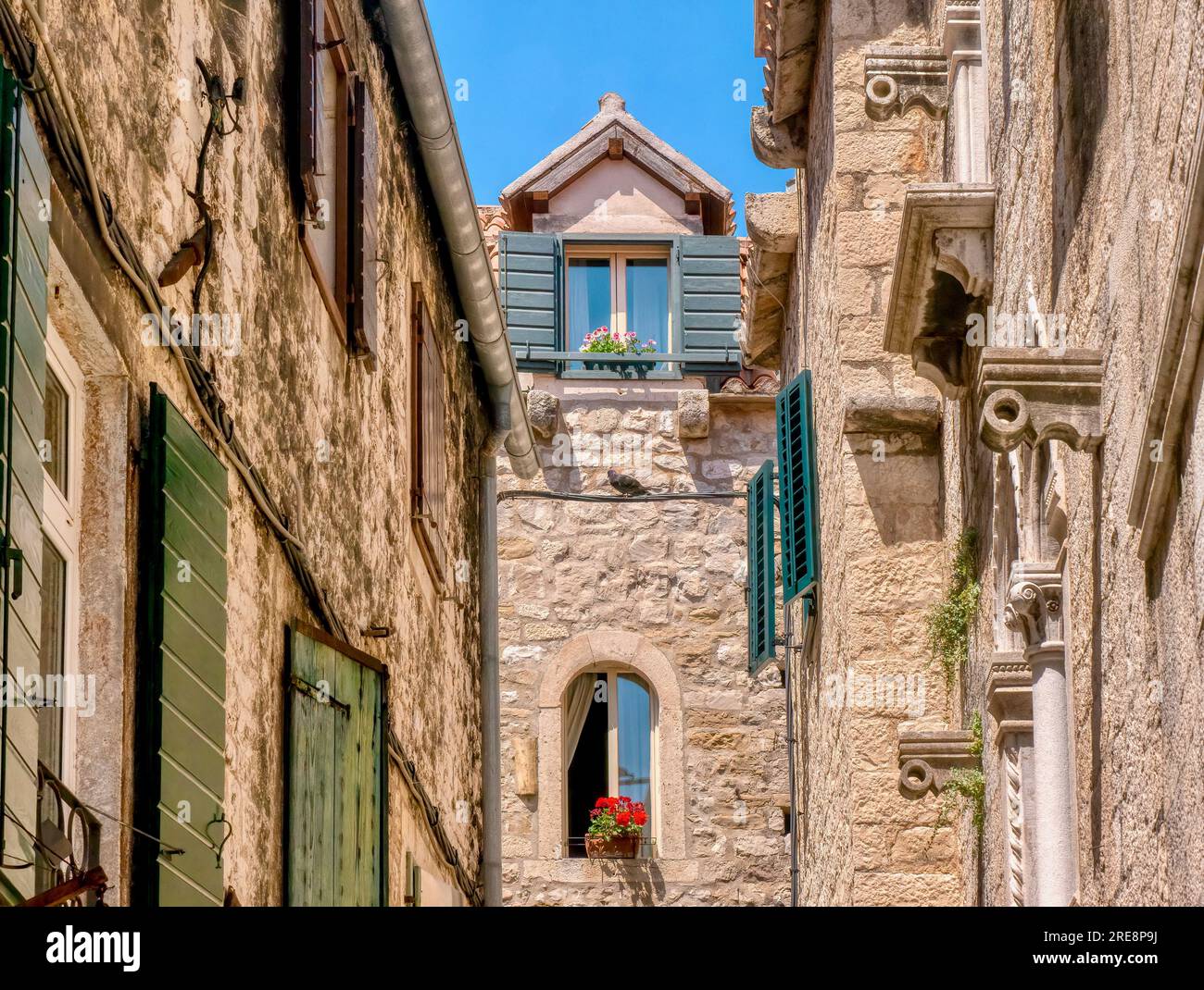 Étages supérieurs de bâtiments résidentiels médiévaux en pierre, avec fenêtres pittoresques à volets et jardinières, dans une ruelle étroite, à Split, Croatie. Banque D'Images
