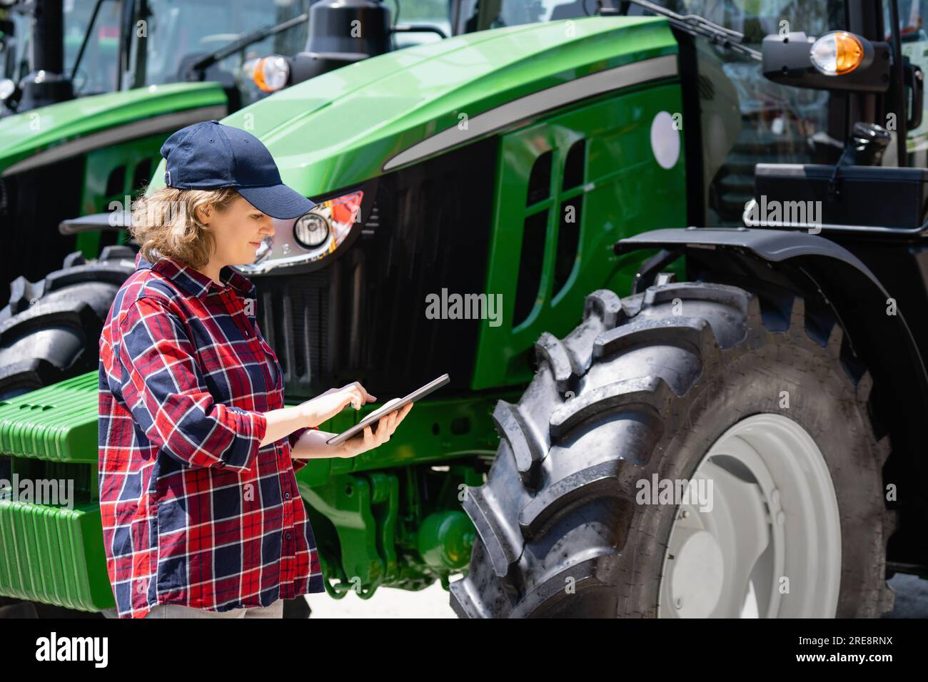 Femme agriculteur avec une tablette numérique sur le fond d'un tracteur agricole. Banque D'Images