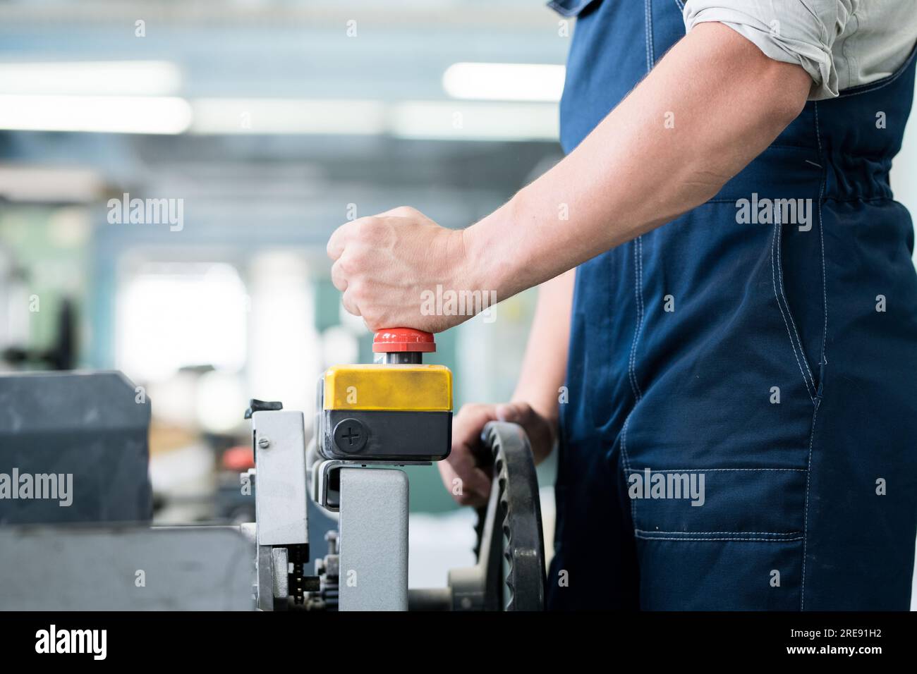 Gros plan d'un ouvrier d'usine méconnaissable dans une machine industrielle fonctionnant avec télécommande, il appuie sur le bouton ed tout en lançant le convoyeur Banque D'Images