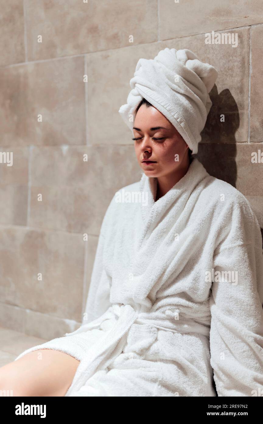 Pensive jeune femme en peignoir blanc sur la t te assis avec les