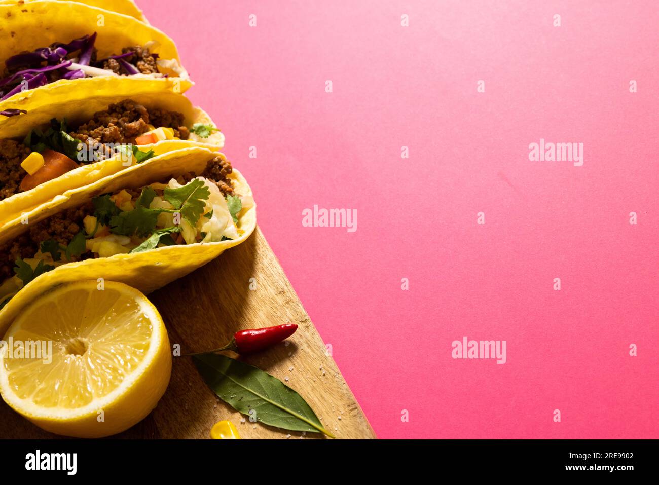 Vue à grand angle des tacos garnis de tranches de citron, de piment rouge et de feuilles sur la planche de service, espace de copie Banque D'Images Vue à grand angle des tacos garnis de tranches de citron, de piment rouge et de feuilles sur la planche de service, espace de copie Banque D'Images