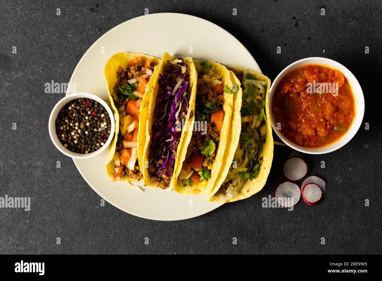 Directement au-dessus du plan de tacos servi dans une assiette avec sauce et poivrons noirs dans des bols sur la table Banque D'Images