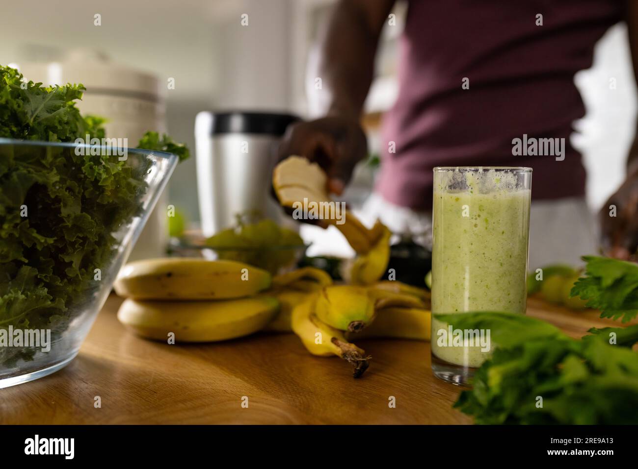 Section médiane de l'homme afro-américain préparant un smoothie sain dans la cuisine à la maison Banque D'Images