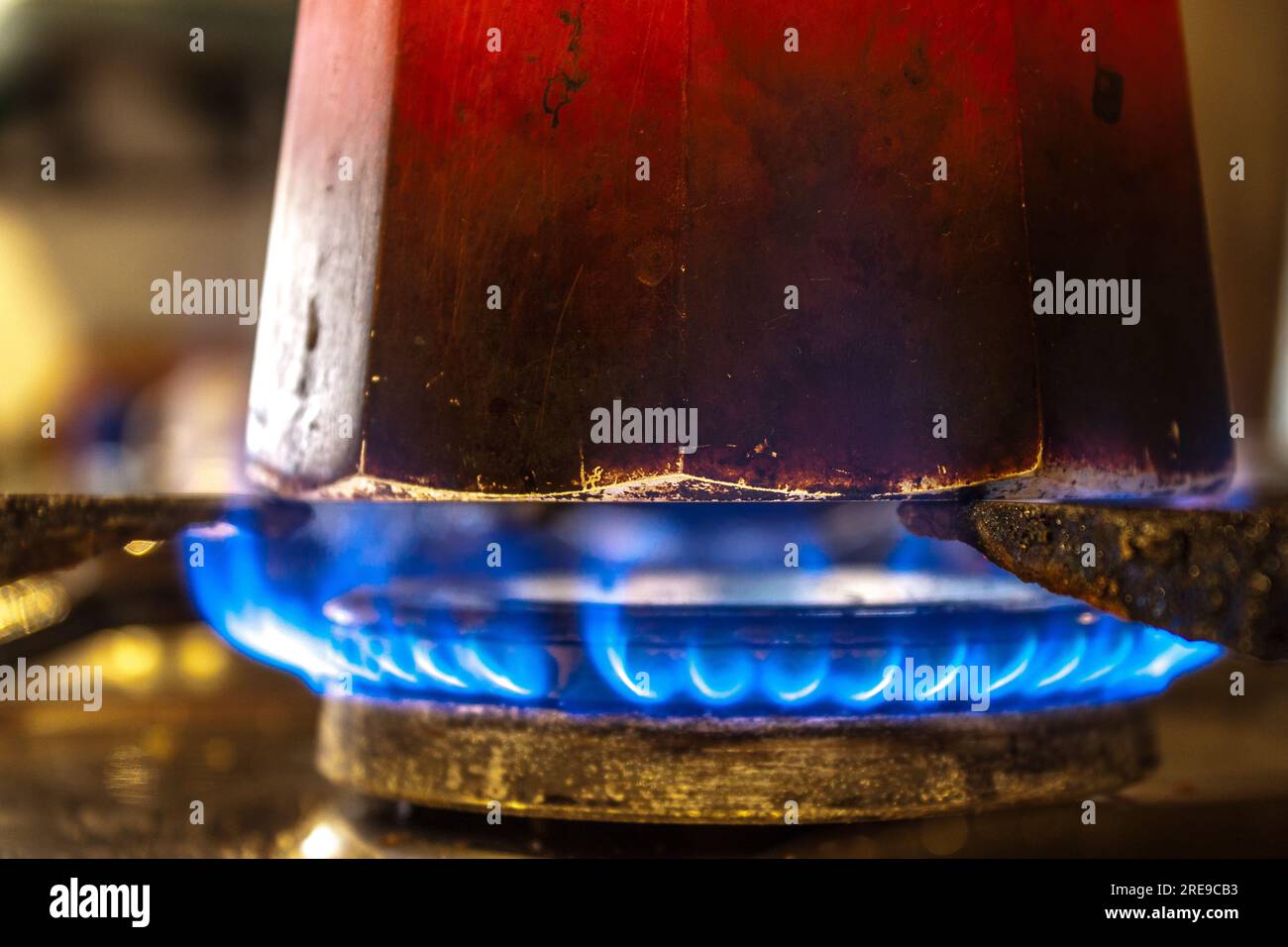 Gros plan de pot moka rouge avec infusion de café sur cuisinière à gaz butane incandescente dans la cuisine Banque D'Images