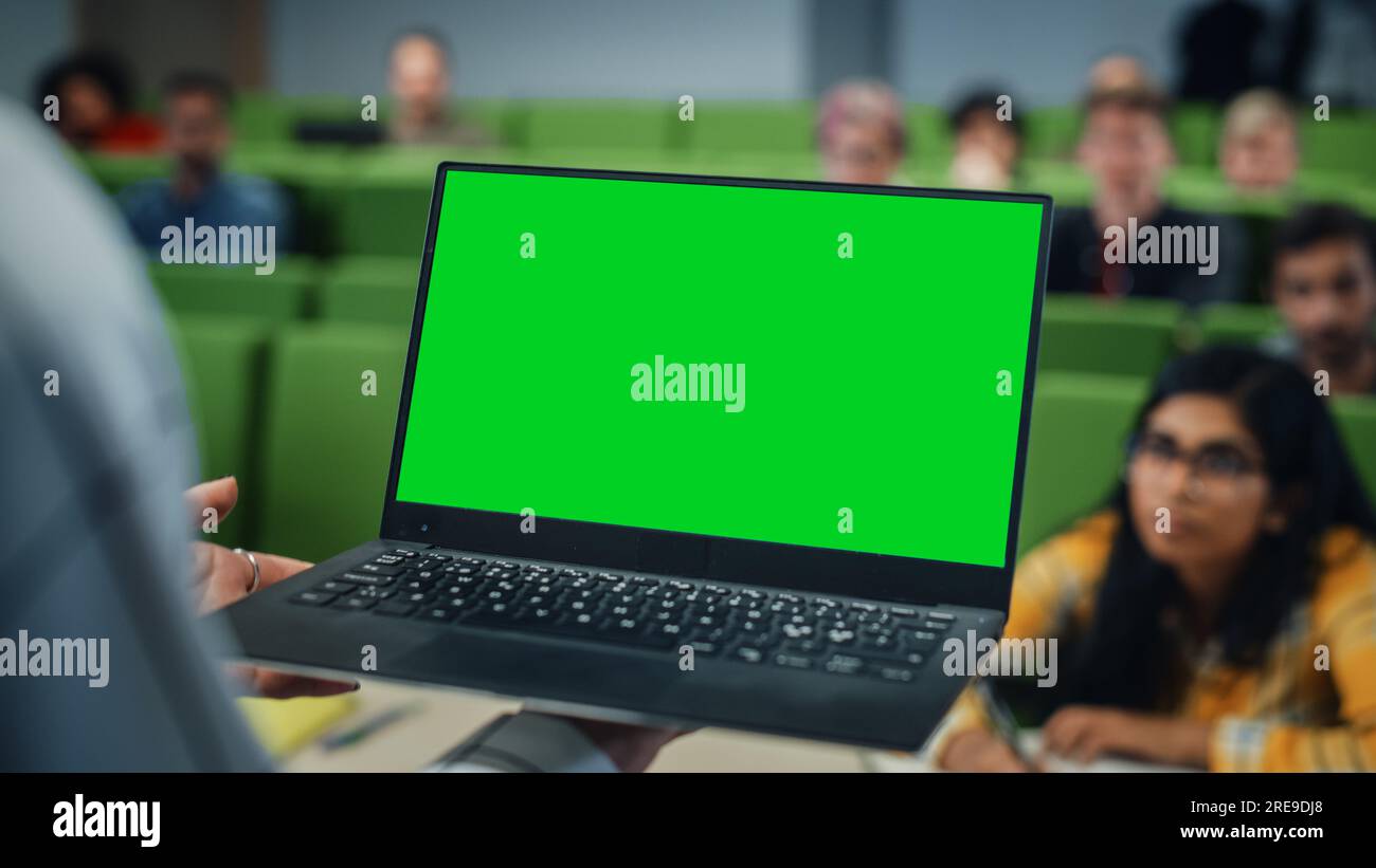 Gros plan d'un professeur d'université utilisant un ordinateur portable avec un écran vert maquette. Enseignante donnant une conférence à une classe Banque D'Images