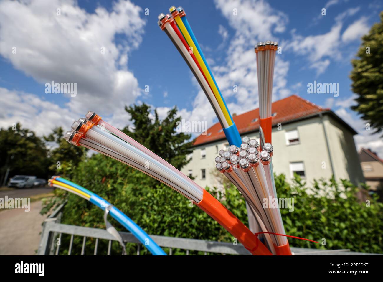 Zwenkau, Allemagne. 26 juillet 2023. Les câbles à fibres optiques dépassent de la base d'une armoire de commande. Envia tel, opérateur de réseau à fibre optique de l'est de l'Allemagne, souhaite connecter environ 80 000 foyers à l'Internet haut débit dans les années à venir. L'objectif est d'atteindre des largeurs de bande allant jusqu'à 1 gigabits par seconde. Des investissements de plus de 350 millions d’euros sont prévus pour cela d’ici 2026. Crédit : Jan Woitas/dpa/Alamy Live News Banque D'Images