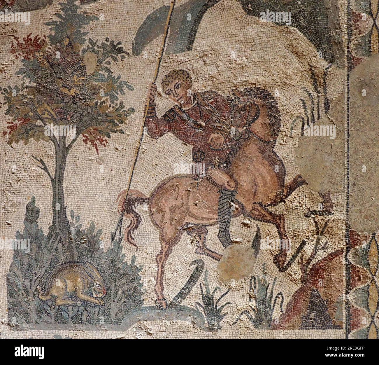 Mosaïque romaine, salle de la petite chasse, Villa Romana del Casale, Sicile, montre un chasseur à cheval frappant un lièvre. Banque D'Images