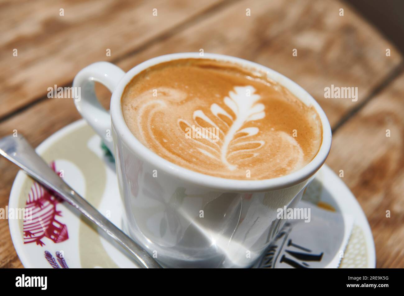 Café avec du lait dans une tasse blanche avec dessin floral sur la surface Banque D'Images