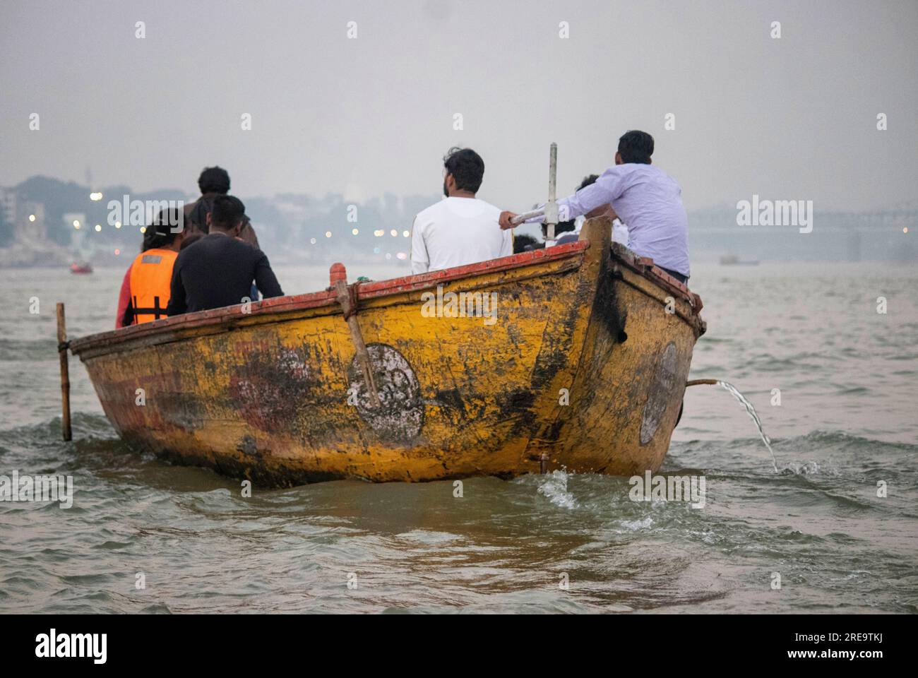 Des gens dans un bateau sur le gange à Veranassi. Les gens préparent des bûchers funéraires à Varanasi sur les rives du Gange, qui est l'une des plus anciennes villes continuellement habitées dans le monde, et la plus sainte des sept villes sacrées de l'hindouisme. Chaque jour, à Manikarnika Ghat, le ghat de crémation le plus grand et le plus propice, environ 100 corps sont incinérés sur des bûchers en bois le long du bord de la rivière. On dit que la flamme éternelle qui alimente les feux brûle depuis des siècles maintenant. Varanasi, Inde. Banque D'Images
