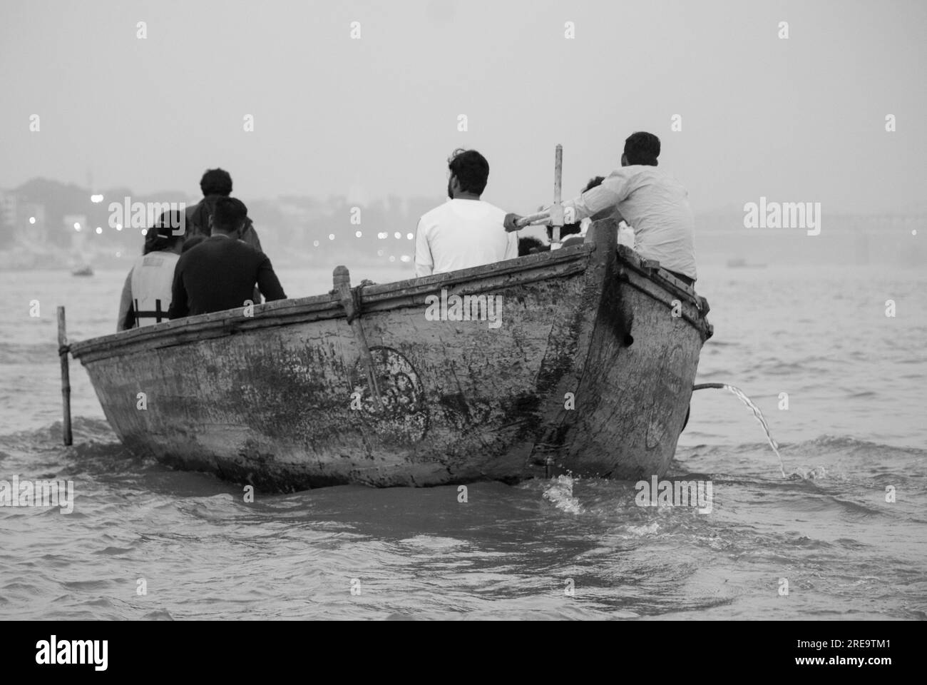 Des gens dans un bateau sur le gange à Veranassi. Les gens préparent des bûchers funéraires à Varanasi sur les rives du Gange, qui est l'une des plus anciennes villes continuellement habitées dans le monde, et la plus sainte des sept villes sacrées de l'hindouisme. Chaque jour, à Manikarnika Ghat, le ghat de crémation le plus grand et le plus propice, environ 100 corps sont incinérés sur des bûchers en bois le long du bord de la rivière. On dit que la flamme éternelle qui alimente les feux brûle depuis des siècles maintenant. Varanasi, Inde. Banque D'Images