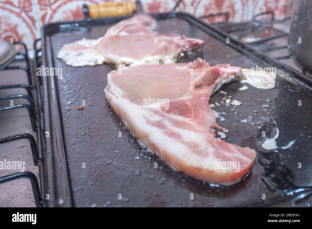 Steak de porc sur un barbecue maison qui est sur le dessus d'un poêle, concept de faire de la nourriture à la maison. Banque D'Images