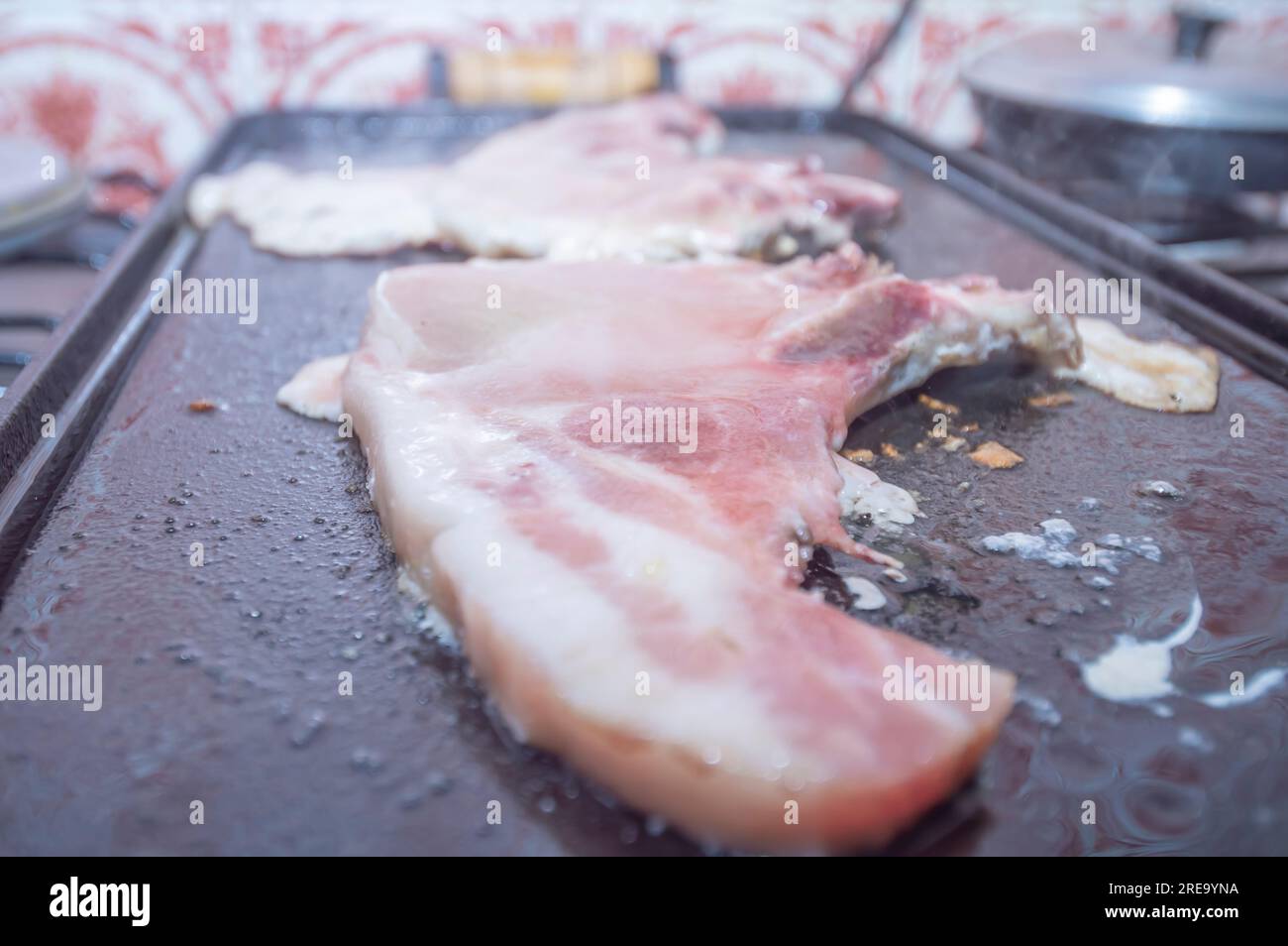 Steak de porc sur un barbecue maison qui est sur le dessus d'un poêle, concept de faire de la nourriture à la maison. Banque D'Images