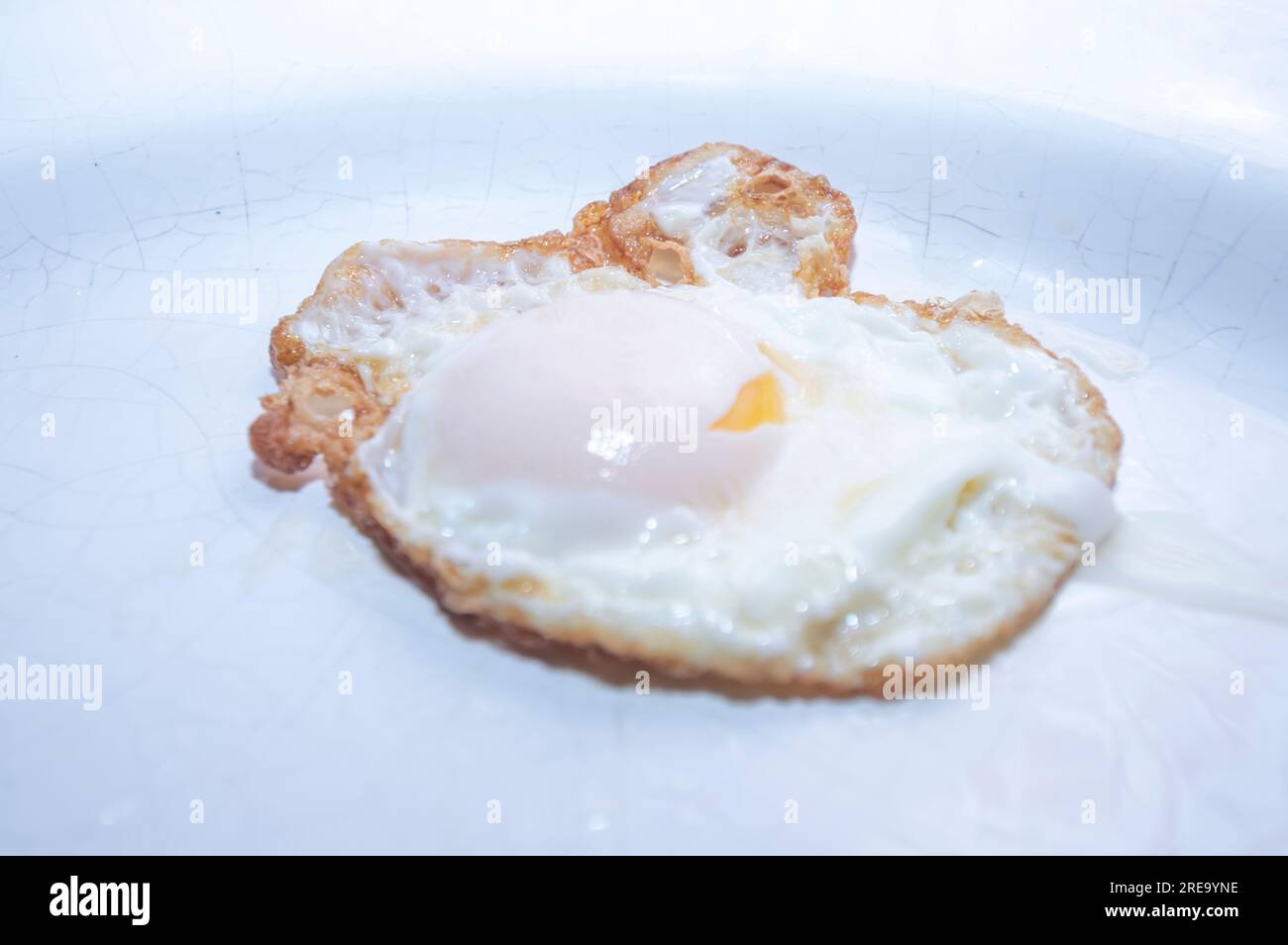 Œuf au plat sur une assiette blanche avec lumière naturelle, photo indiquée pour la culture. Banque D'Images
