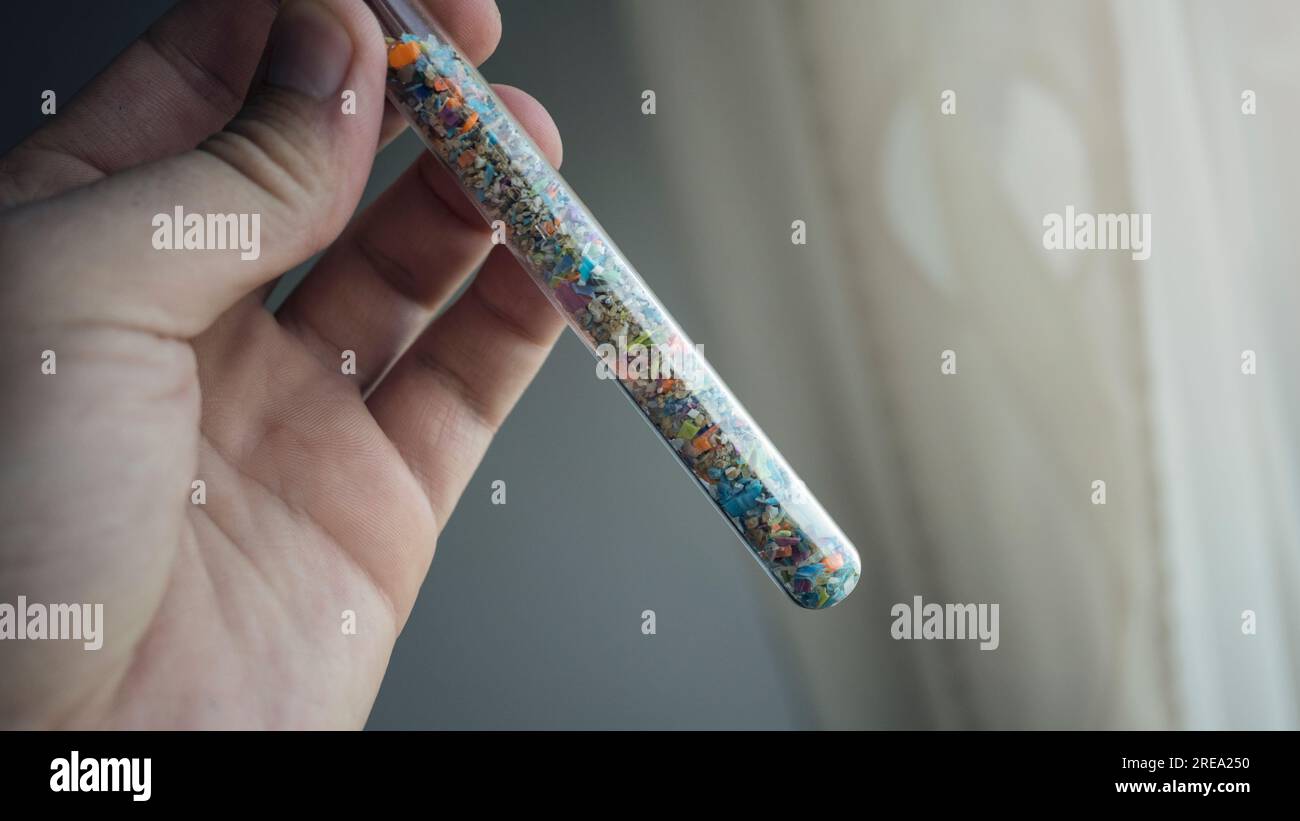Macro shot d'un tube à essai rempli de micro plastiques collectés sur la plage. Concept de pollution de l'eau et de gestion des déchets industriels. Banque D'Images