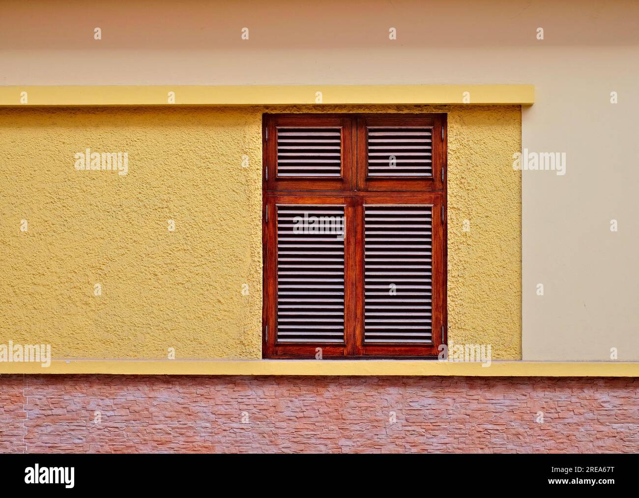 Simple fenêtre en bois dans un mur jaune chaud d'une maison de villa. Banque D'Images