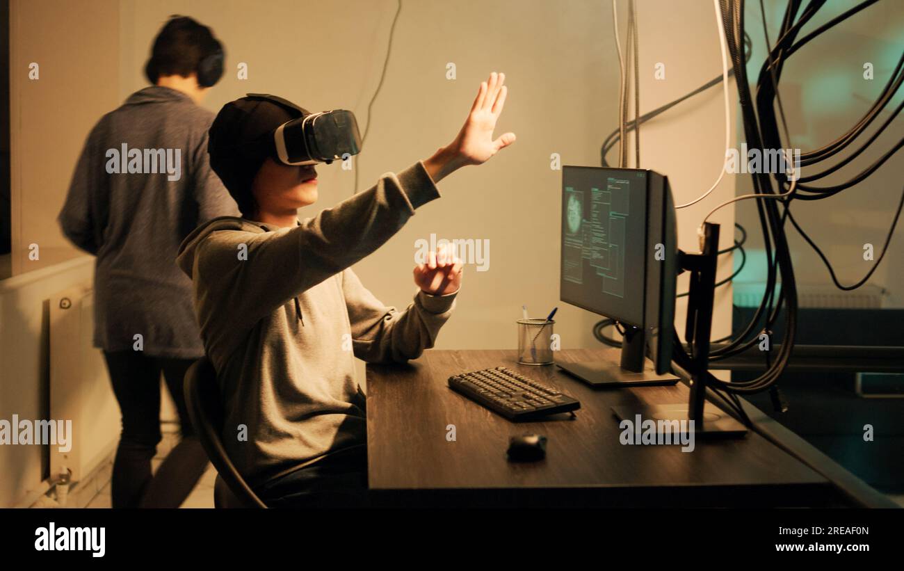 Cyber criminel travaillant avec des lunettes 3d vr pour craquer le cryptage du pare-feu, en utilisant un casque de réalité virtuelle pour pirater le système gouvernemental. Pirate masculin brisant le réseau avec des logiciels malveillants et des virus. Banque D'Images