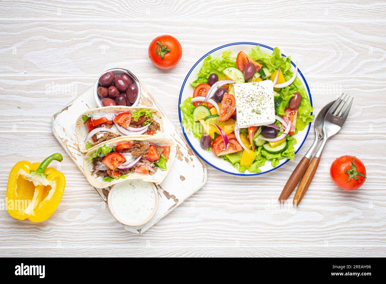 Cuisine grecque traditionnelle : salade grecque, gyros à la viande et aux légumes, sauce Tzatziki, olives sur fond de table en bois rustique blanc d'en haut Banque D'Images