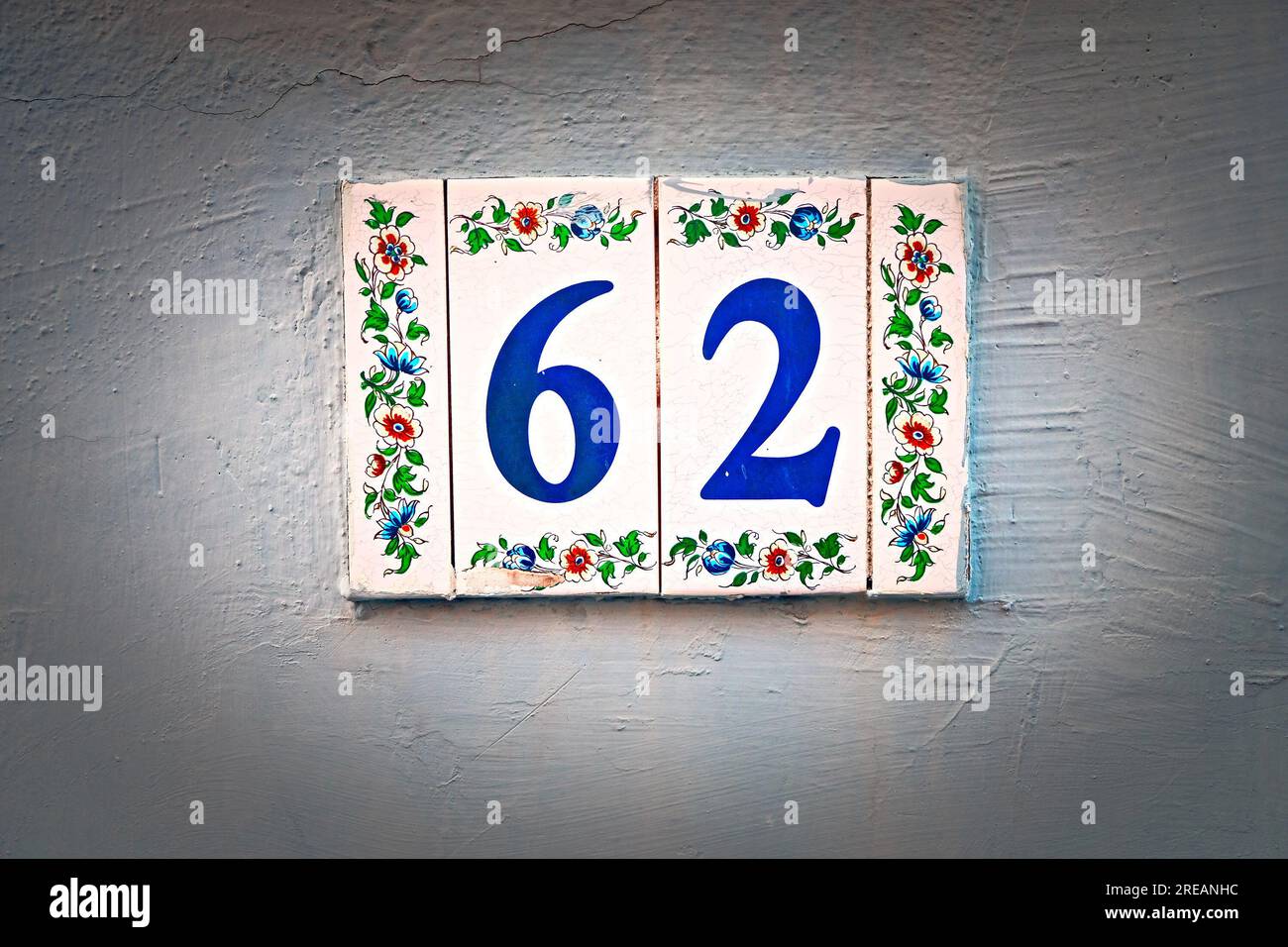 62, numéro soixante-deux, chiffres bleus sur carreaux floraux, vignettés. Banque D'Images