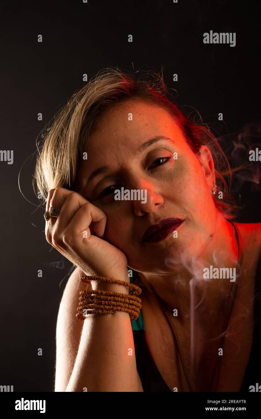 Belle et belle femme calme regardant la caméra avec ses mains sur son visage. Fumée d'Encens tout autour. Portrait de studio. Isolé sur un b noir Banque D'Images