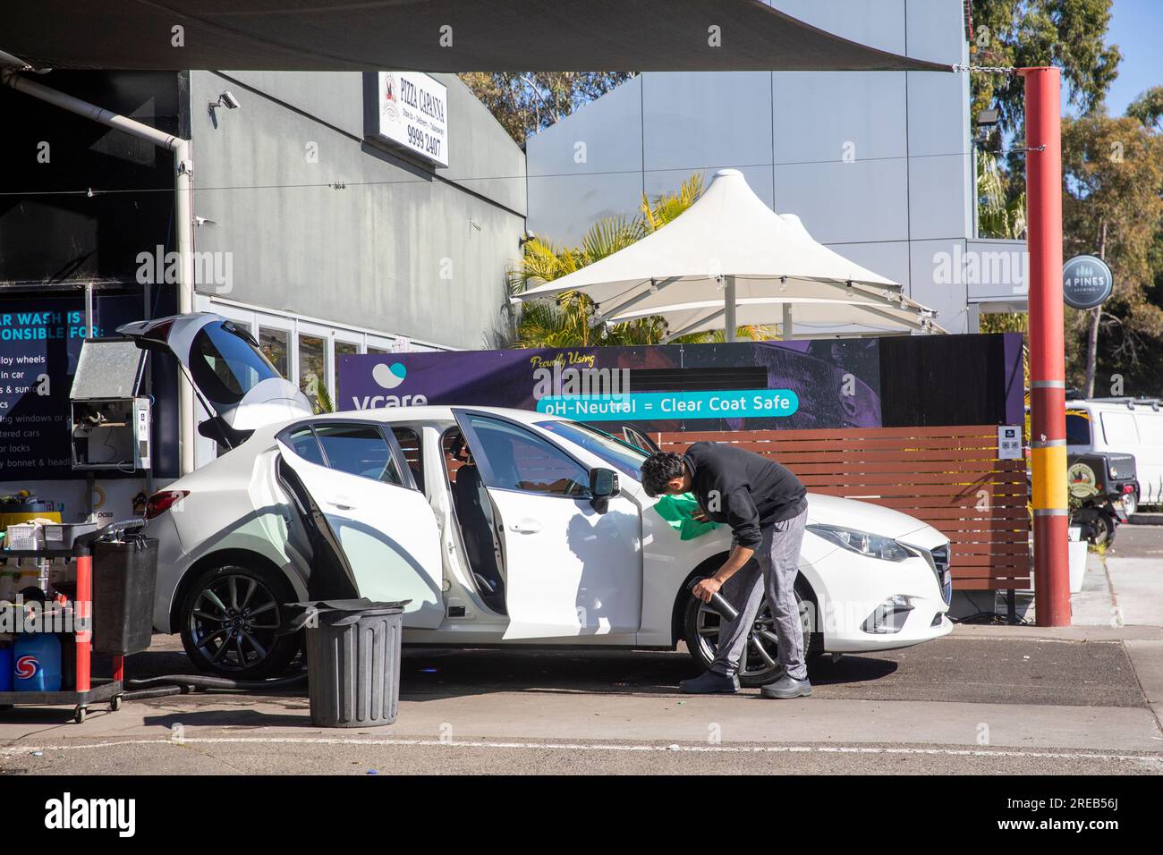 Service de lavage de voiture à la main à Sydney Australie, employé à lavage de voiture nettoie une voiture blanche avec les portes ouvertes, Australie, 2023 Banque D'Images