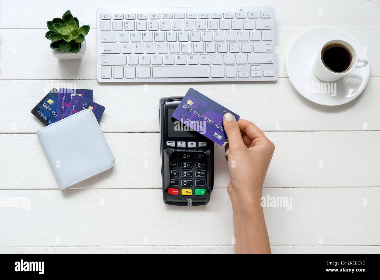Main féminine avec terminal de paiement, clavier et cartes de crédit sur  fond en bois blanc Photo Stock - Alamy
