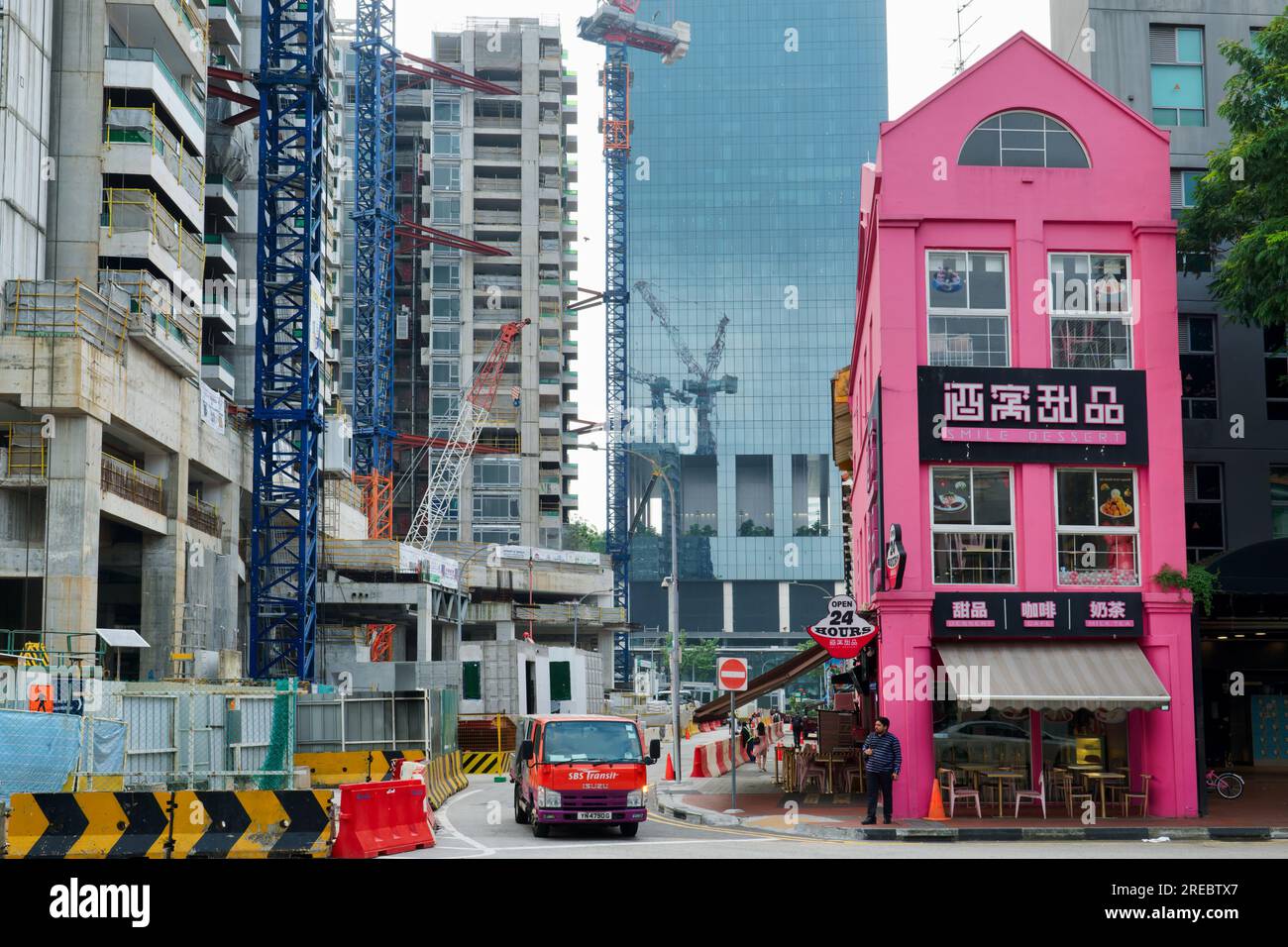 Construction de grande hauteur en cours dans le quartier de Bugis, Singapour, un vieux bâtiment rose abritant un magasin Smile dessert offrant un contraste frappant dans le style Banque D'Images