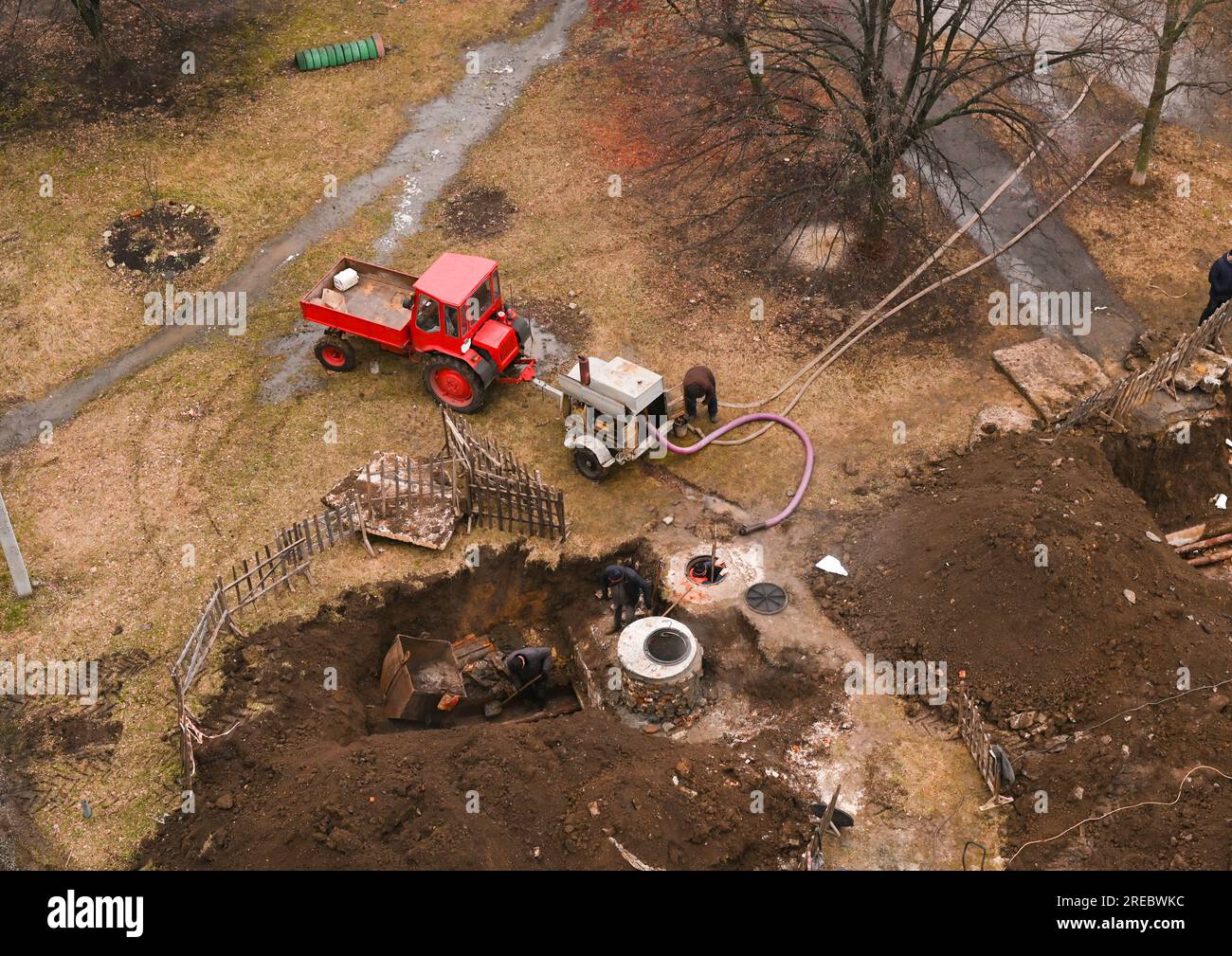 réparation de tuyaux d'égout de communications dans un puits d'égout creusé. pompage de l'eau d'un puits d'égout. le tracteur attirait un gros compresseur industriel. plu Banque D'Images