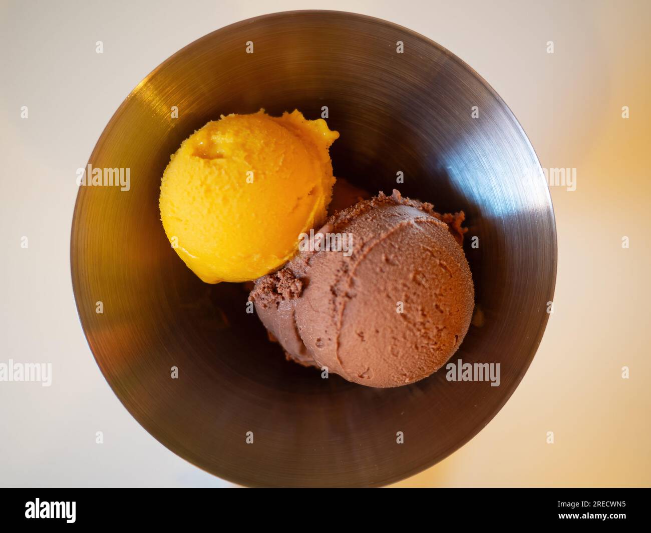 Deux boules de crème glacée dans un bol en métal - une boule de mangue et une boule de chocolat. Banque D'Images