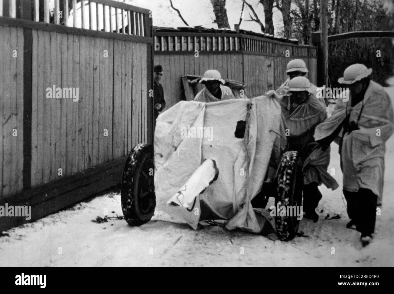 Les soldats de la Waffen-SS poussent un Pak 36 de 3,7 cm en position. Pistolet et hommes sont camouflés de fortune avec un tissu blanc. Photo : Rauties. [traduction automatique] Banque D'Images