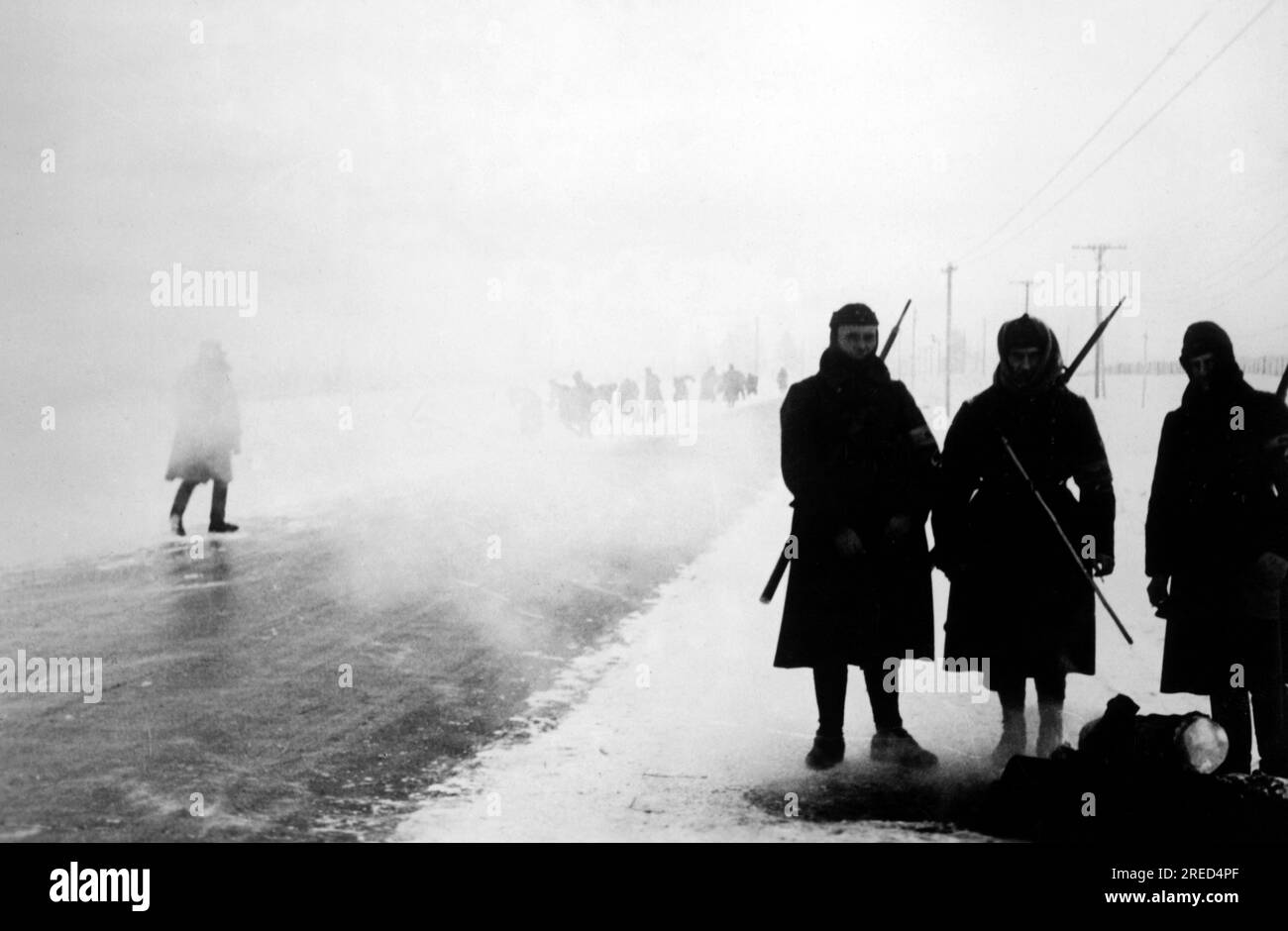 Des soldats allemands de l'organisation Todt se réchauffent sur la piste Leningrad-Moscou. En arrière-plan, les prisonniers de guerre russes dégagent la neige de la route. Photo : Burkhardt. [traduction automatique] Banque D'Images
