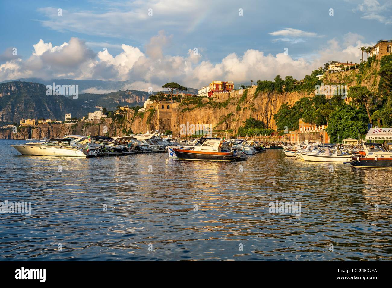 Bateaux amarrés à Marina Piccola baignés de lumière dorée alors que le soleil se couche à travers la baie de Naples à Sorrente dans la région Campanie du sud-ouest de l'Italie Banque D'Images