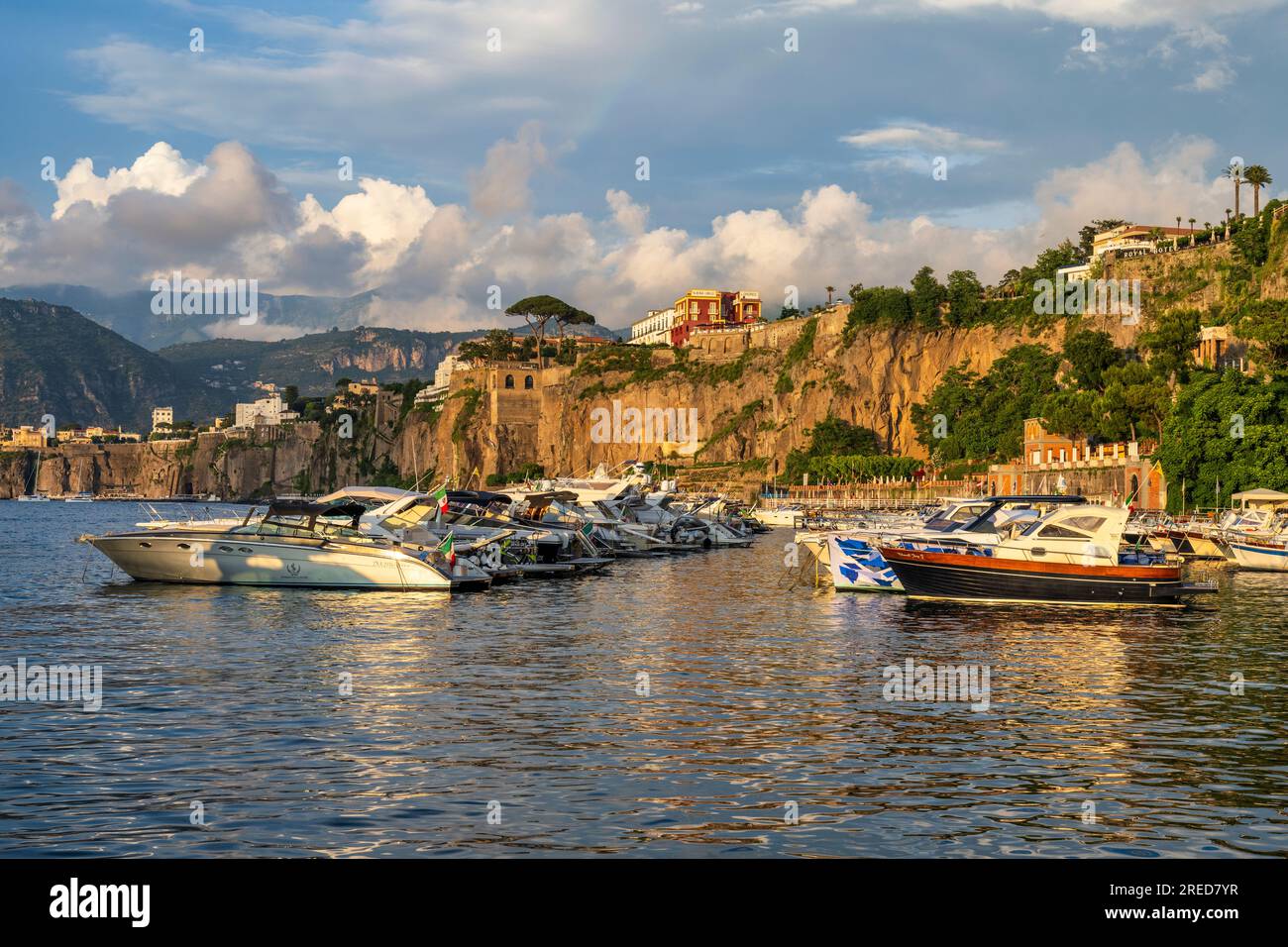 Bateaux amarrés à Marina Piccola baignés de lumière dorée alors que le soleil se couche à travers la baie de Naples à Sorrente dans la région Campanie du sud-ouest de l'Italie Banque D'Images