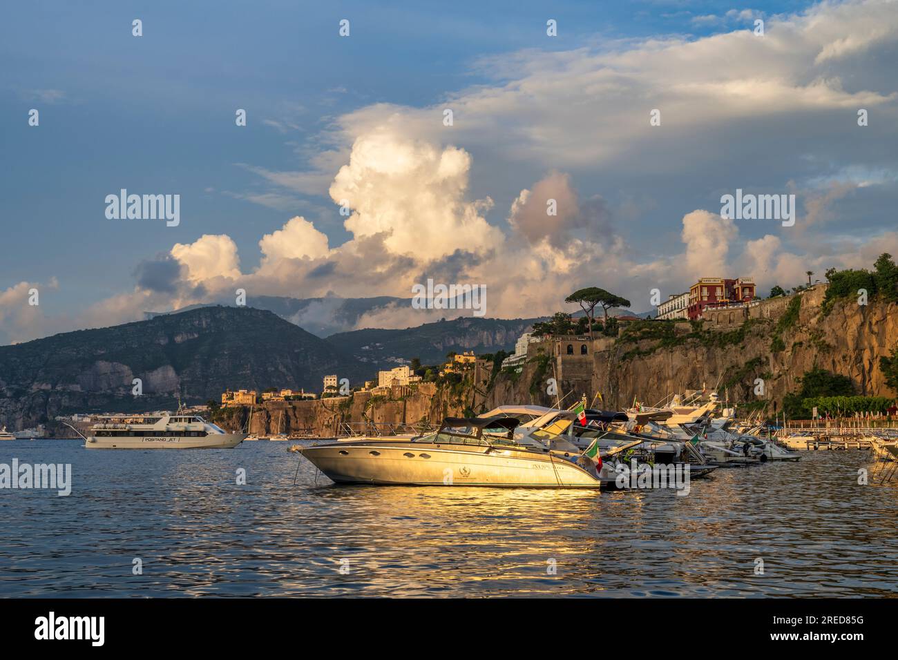 Bateaux amarrés à Marina Piccola baignés de lumière dorée alors que le soleil se couche à travers la baie de Naples à Sorrente dans la région Campanie du sud-ouest de l'Italie Banque D'Images