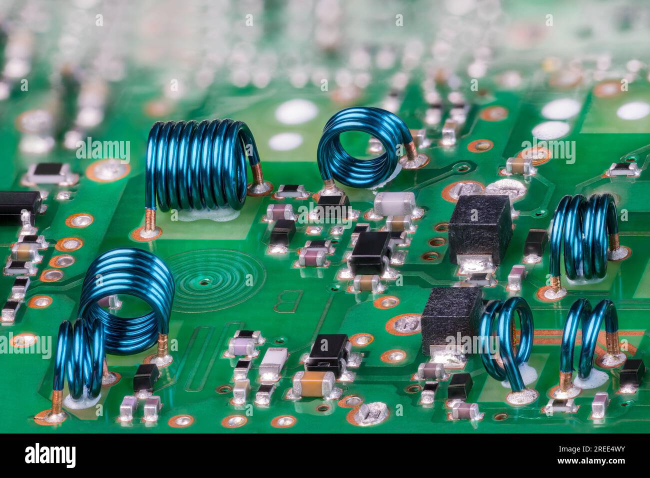 Inductances à noyau d'air bleu à partir d'un fil métallique sur une carte de circuit imprimé verte du module RF de carte TV. Bobine spirale plane en gros plan et composants électroniques. PCB Banque D'Images