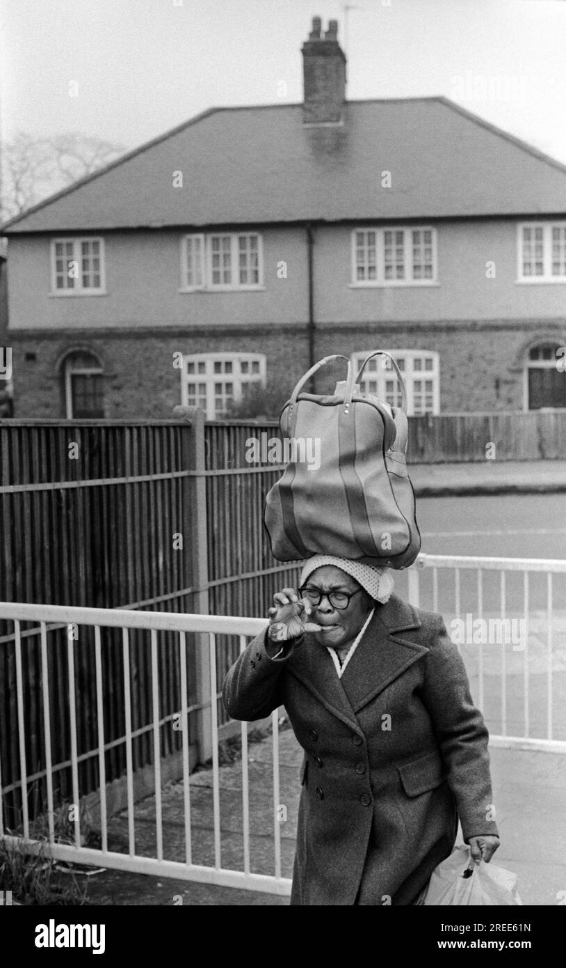 Femme britannique noire rentre à la maison du centre commercial Arndale transportant ses achats dans un sac sur la tête. Elle me fait une sorte de geste de la main. Wandsworth sud de Londres, Angleterre vers 1979. ANNÉES 1970 ROYAUME-UNI HOMER SYKES Banque D'Images