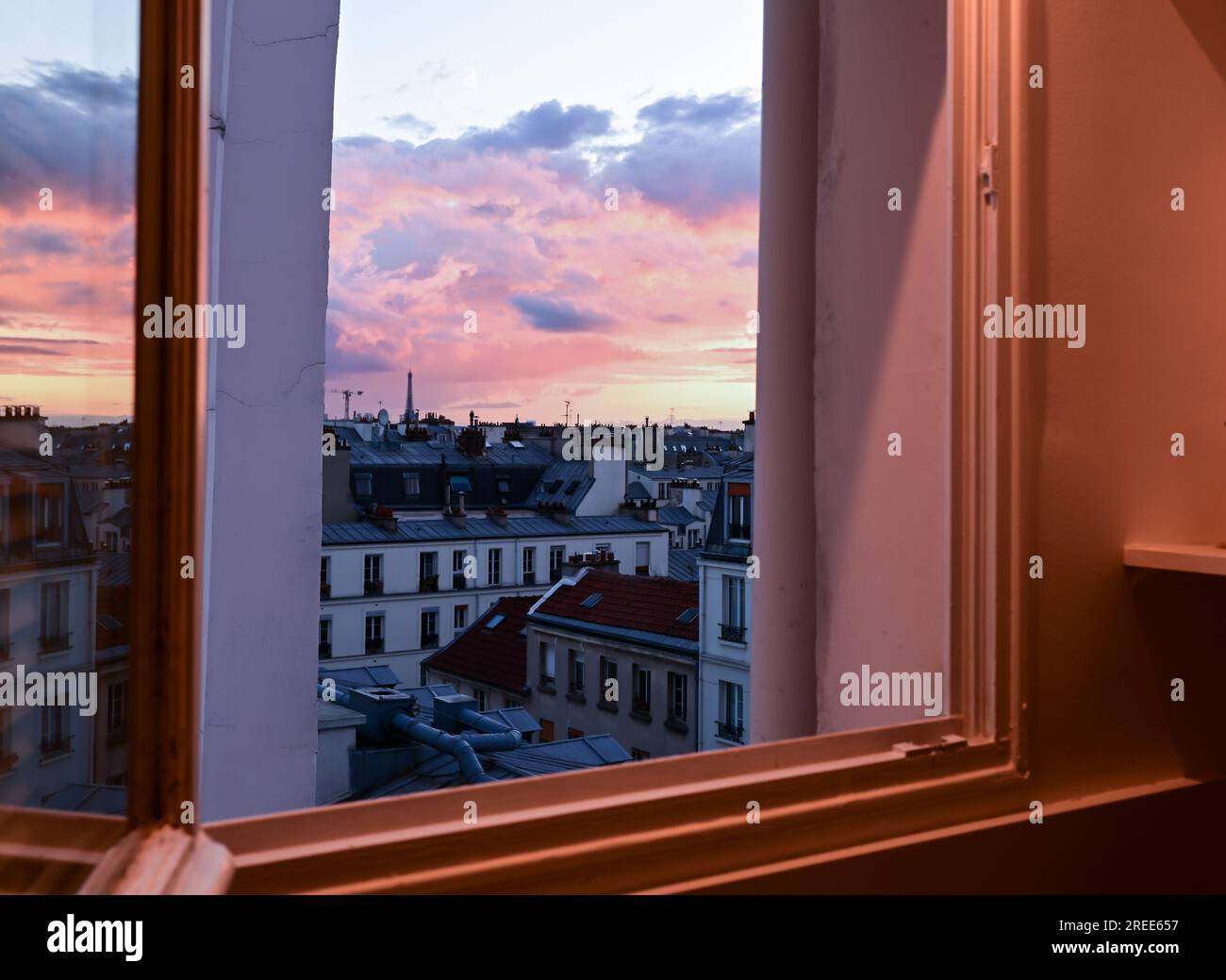 Paris France juin 2022. Vue depuis la fenêtre d'un coucher de soleil envoûtant sur la ville. Reconnaissable la tour Eiffel qui se démarque parmi les toits de t Banque D'Images