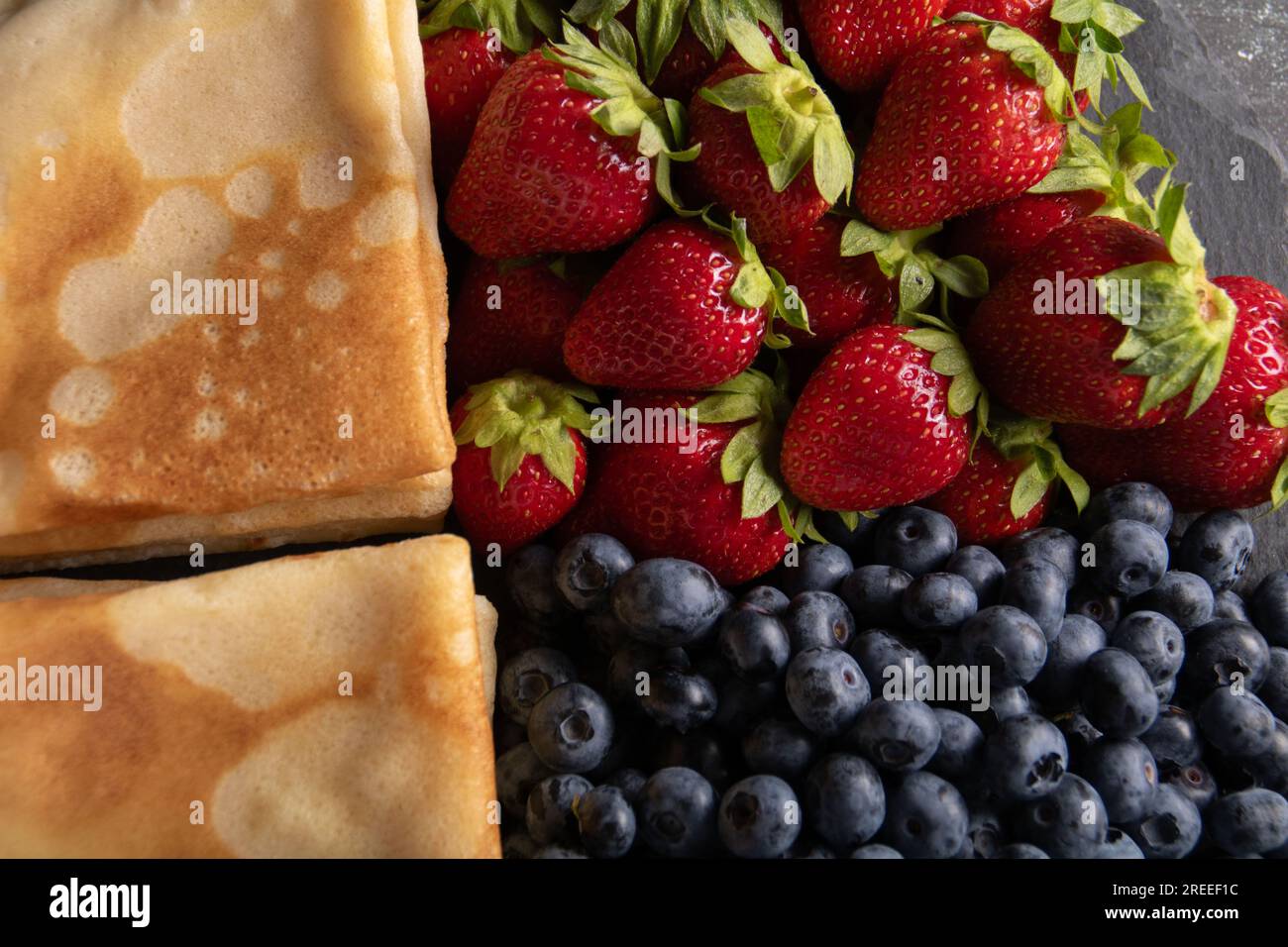 photo de crêpes minces avec fraises mûres et bleuets gros plan Banque D'Images