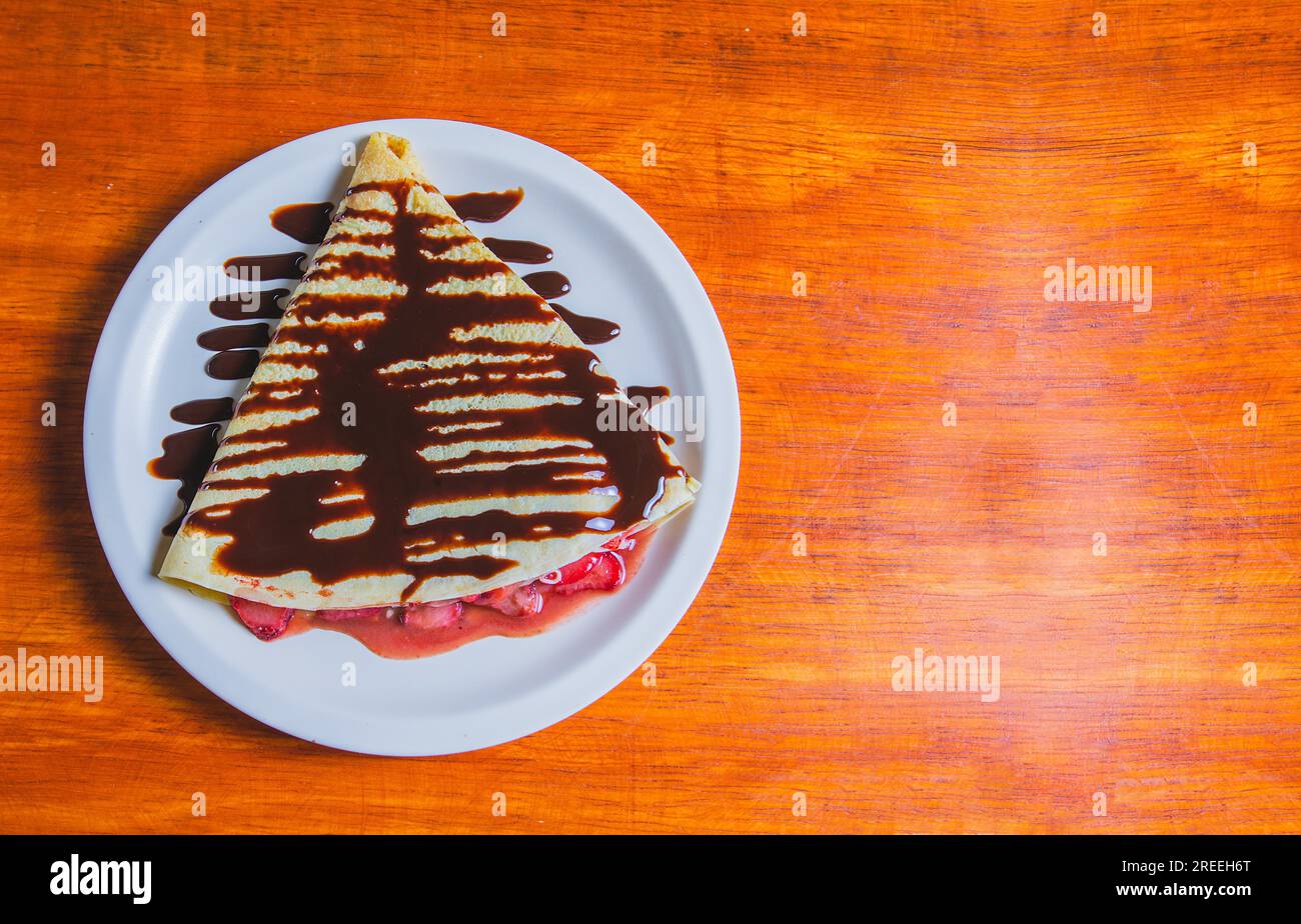 Crêpe à la crème au chocolat et fraise sur table en bois. Crêpe de fraise sucrée avec de la crème au chocolat sur la table en bois Banque D'Images