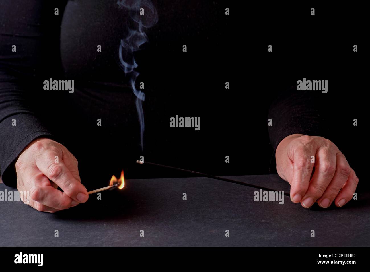 Mains de femmes allumant un bâton d'encens avec une allumette Banque D'Images