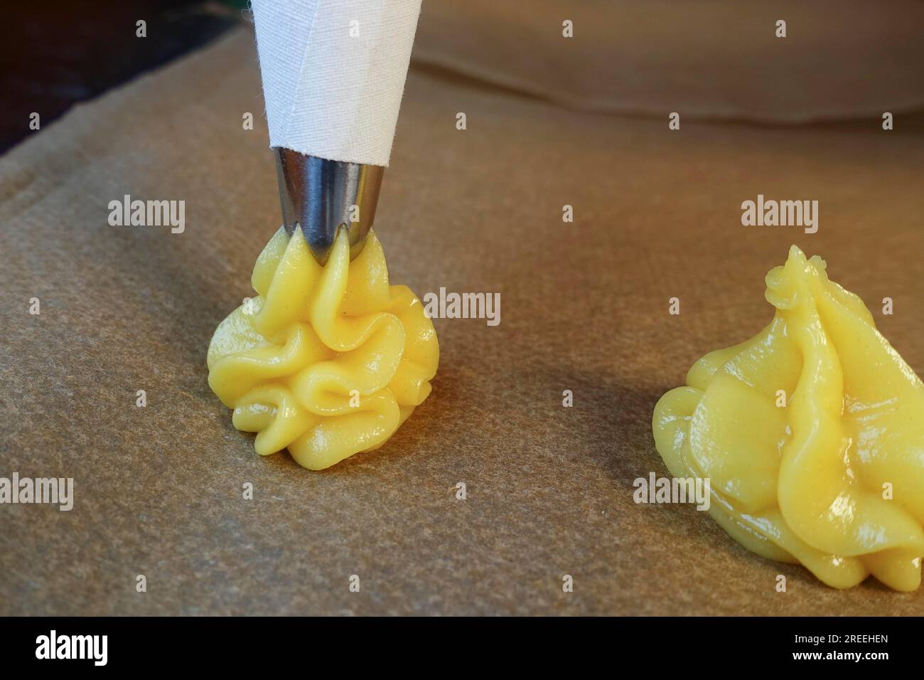 Cuisine souabe, préparation de mini-bouffées à la crème, presser la pâte à choux crue à travers un sachet à passepoil sur du papier sulfurisé, des échairs, des profiteroles, des pâtisseries bordées Banque D'Images