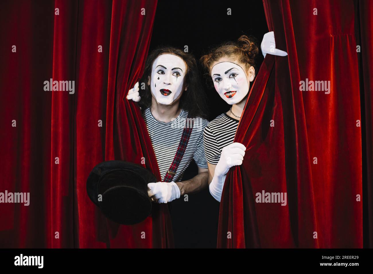 Deux artistes mime jetant un coup d'œil à travers le rideau rouge. Résolution et haute qualité belle photo Banque D'Images