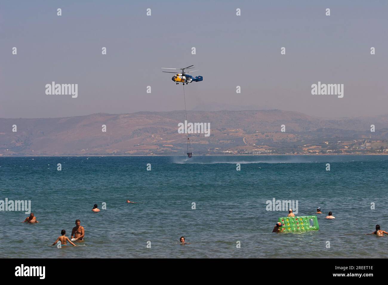 Hélicoptère, hélicoptère, hélicoptère de lutte contre l'incendie, incendie, hélicoptère ravitaillant en eau de la mer, touristes de baignade, Georgioupolis, Crète, Grèce Banque D'Images