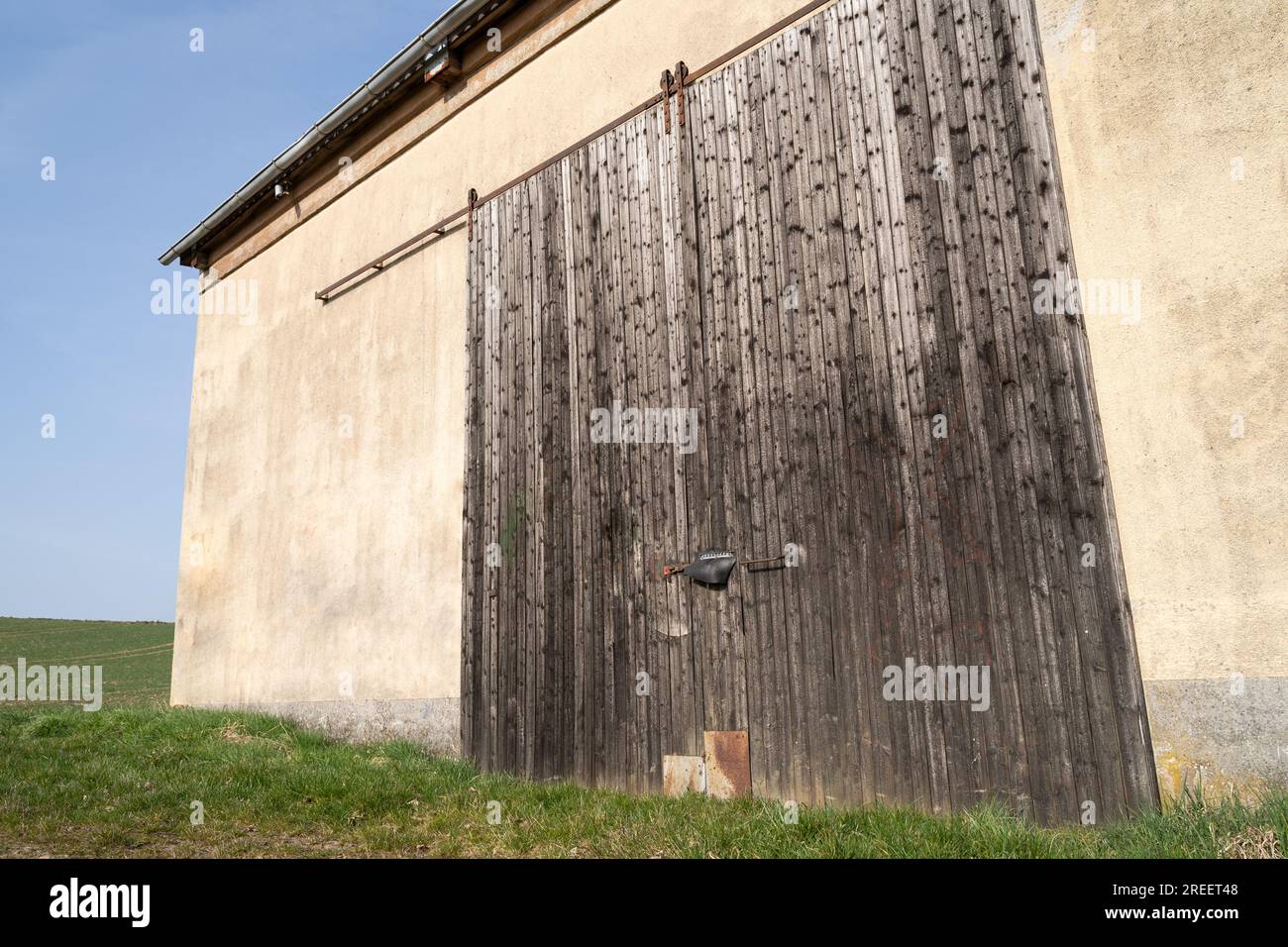 Grange avec vieilles portes en bois dans les terres agricoles par une journée ensoleillée au printemps Banque D'Images