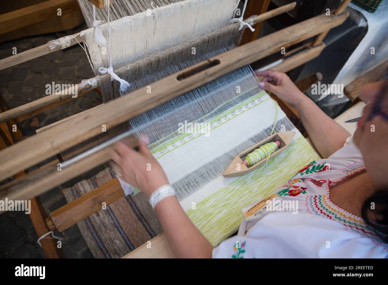 KEZMAROK, SLOVAQUIE - juillet 9, 2023 : artisan traitant le coton sur un métier à tisser traditionnel en bois au Festival européen du folklore et de l'artisanat à Kezmaro Banque D'Images