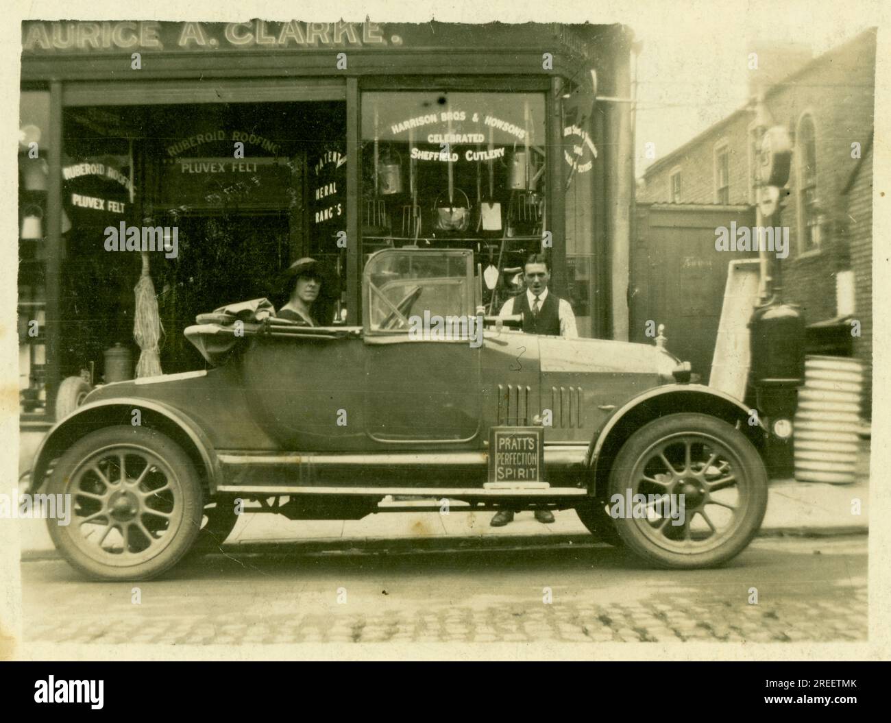 Original des années 1920 petite carte postale Maurice A. Clarke Ironmongers / quincaillerie - petite entreprise familiale - la femme du propriétaire est assise dans la voiture, Morris Cowley 'Bullnose' ouvert 2 places - peut-être montrant la nouvelle voiture familiale. Londres Royaume-Uni Circa 1925. Banque D'Images
